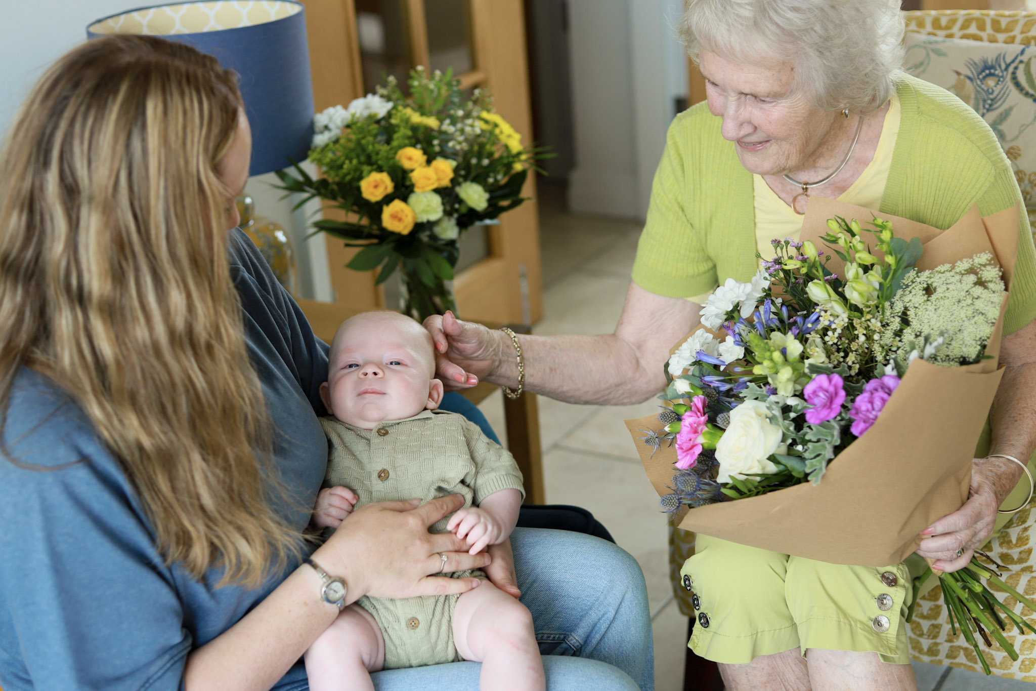 Same day flower delivery bouquet in foreground with mum and newborn